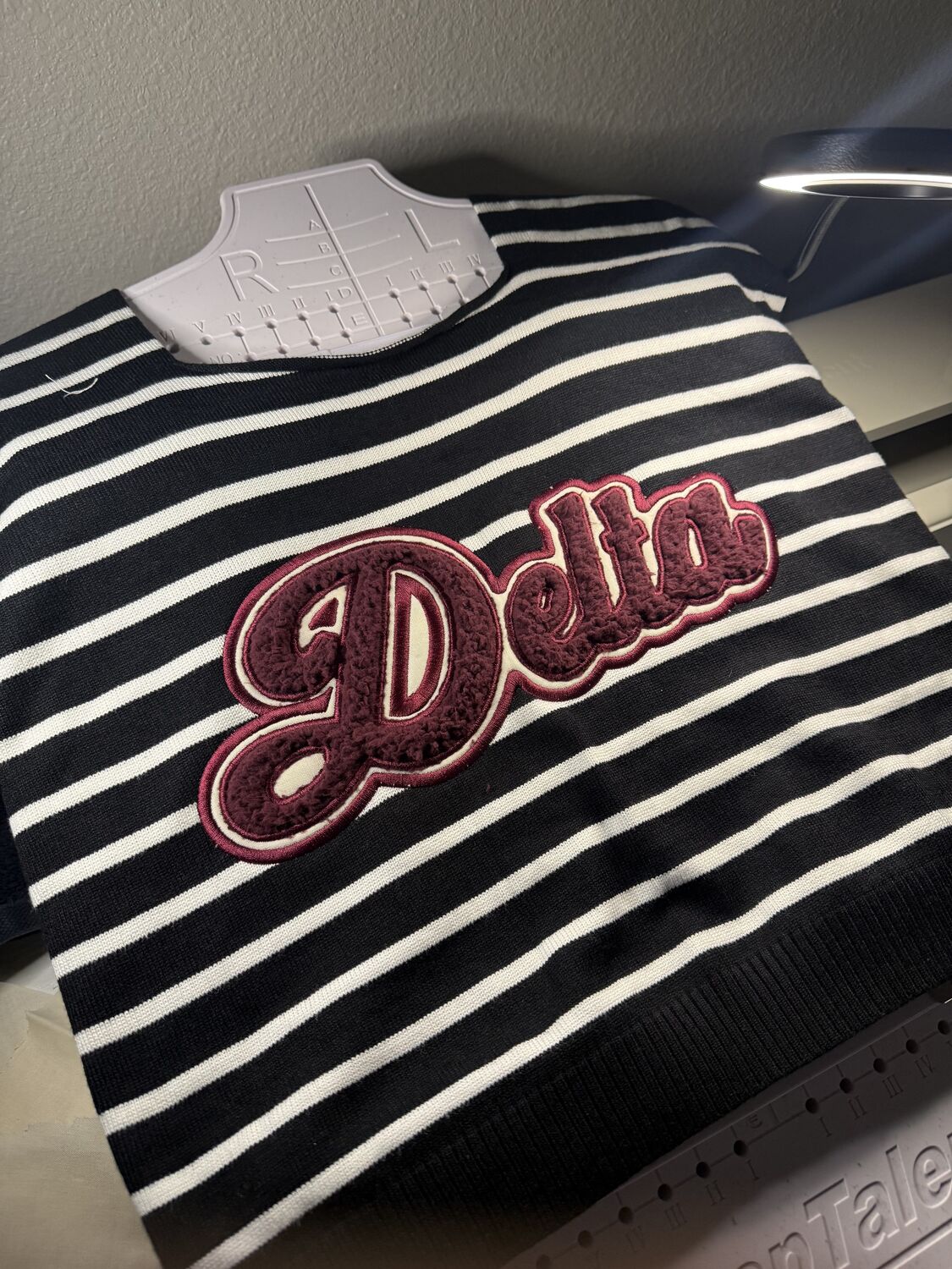 Delta chenille script on a black and white striped sweater